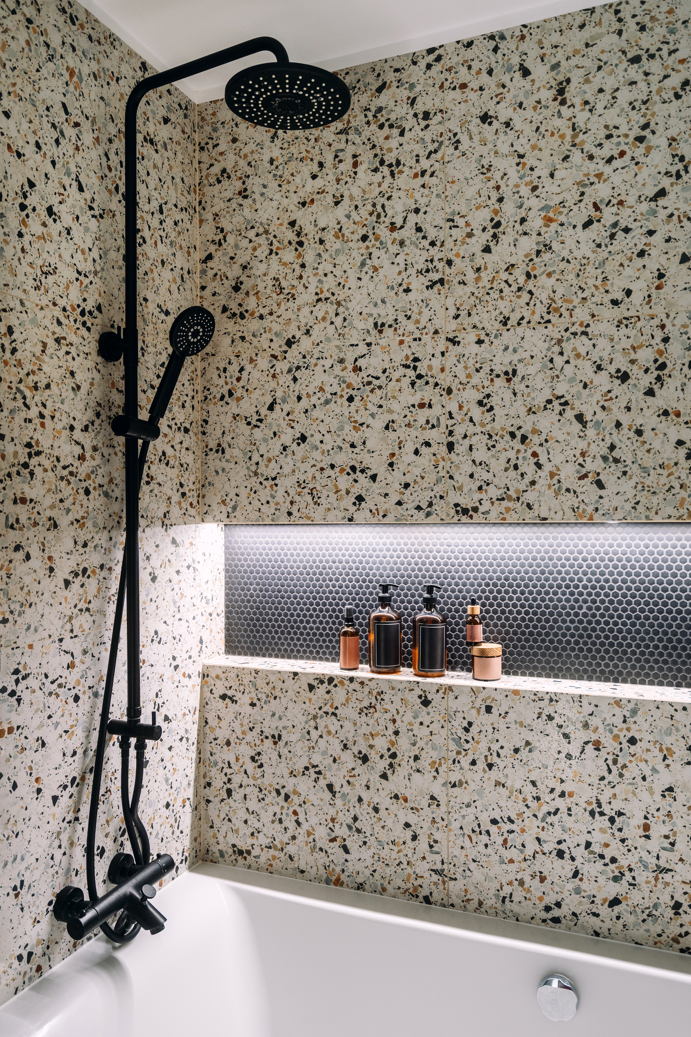 Douche à pommeau noir dans une salle de bains au revêtement terrazzo