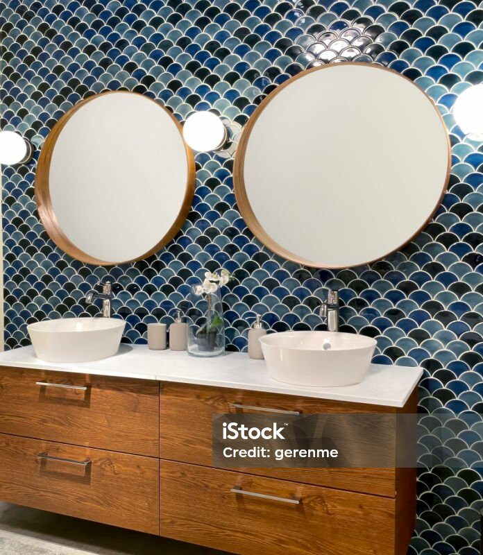 Mur en zellige bleu à motifs écailles dans une salle de bains avec double vasque et meuble en bois