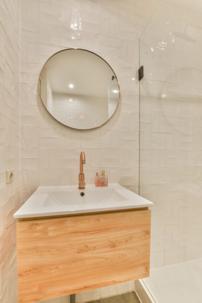 Salle de bains avec carrelage mural en zellige crème, meuble vasque en bois clair et robinetterie cuivrée