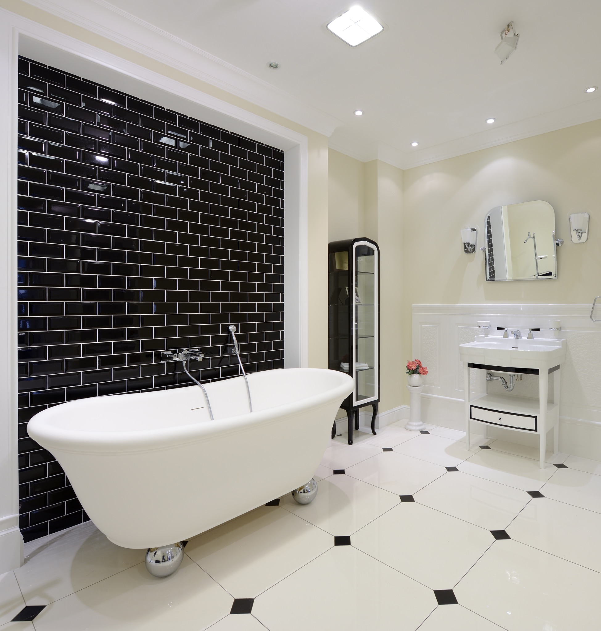 Salle de bains rétro avec carrelage métro noir, baignoire sur pieds et sol cabochon