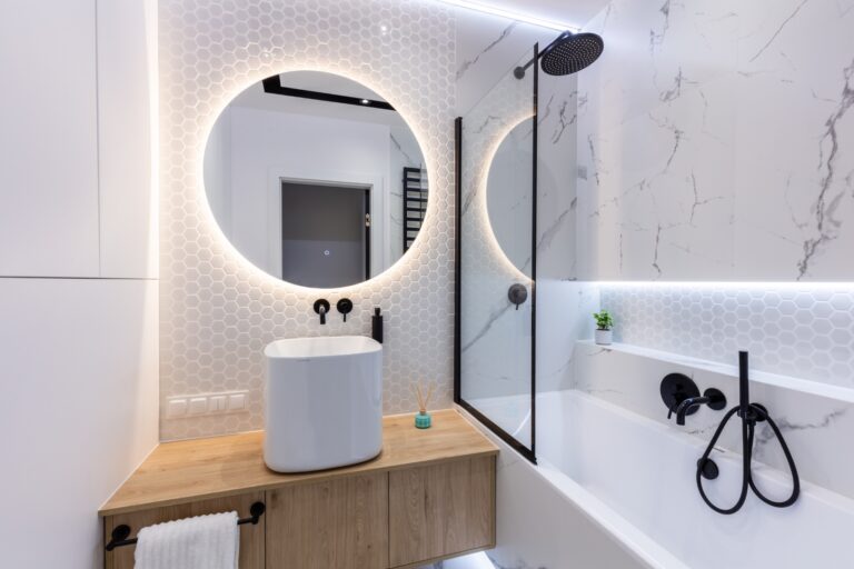 Salle de bains moderne avec une douche-baignoire équipée d'un pare-baignoire en verre, d'une robinetterie noire et d'un meuble en bois avec vasque design