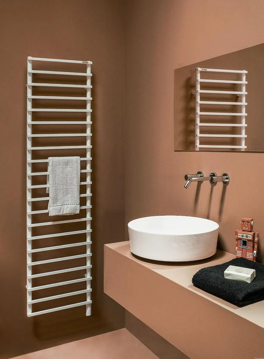 Sèche-serviettes échelle blanc installé dans une salle de bains couleur terracotta avec vasque ronde et robinet mural