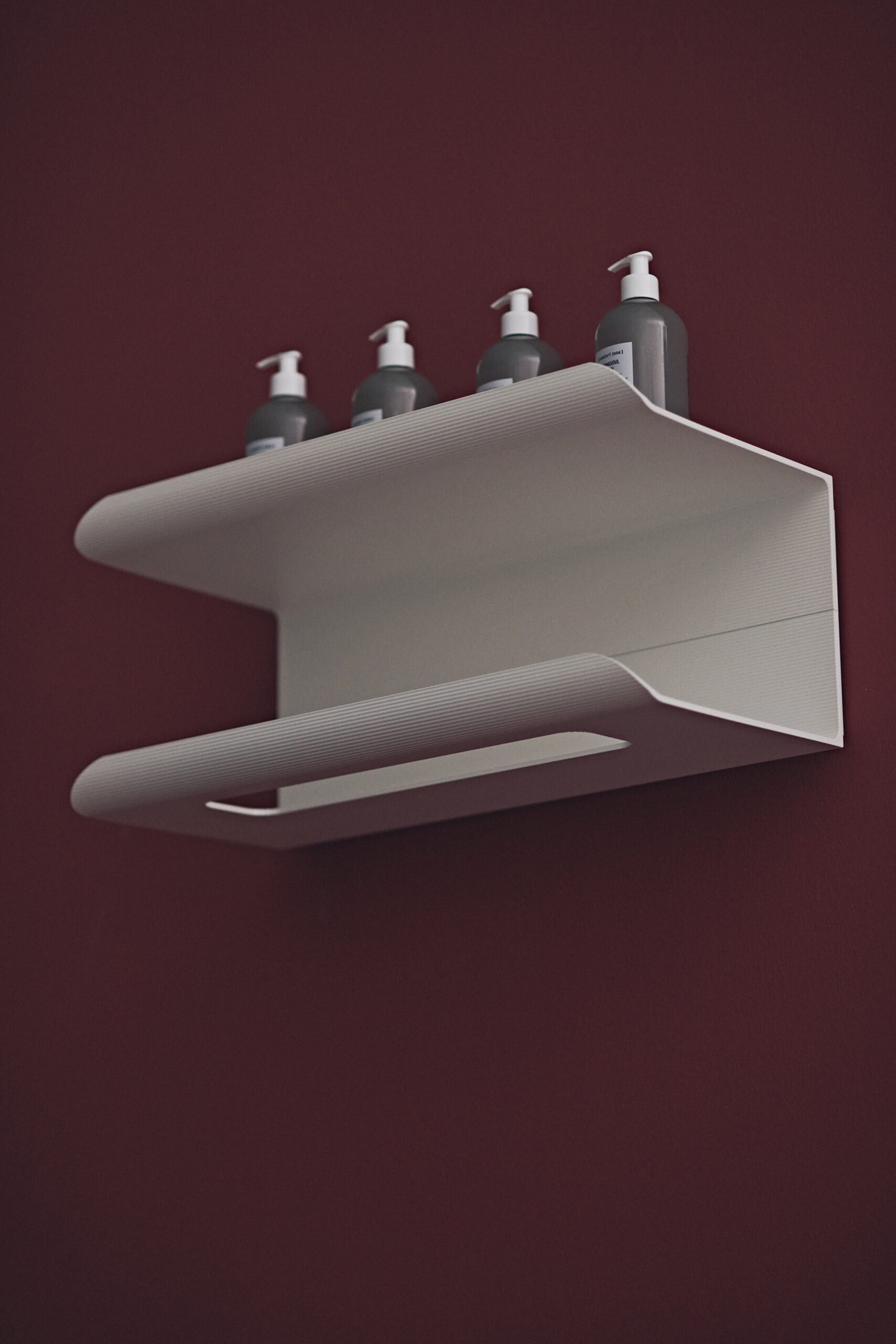 Sèche-serviettes mural design JJ de la marque Tubes, blanc mat, avec fonction étagère, installé sur un mur bordeaux