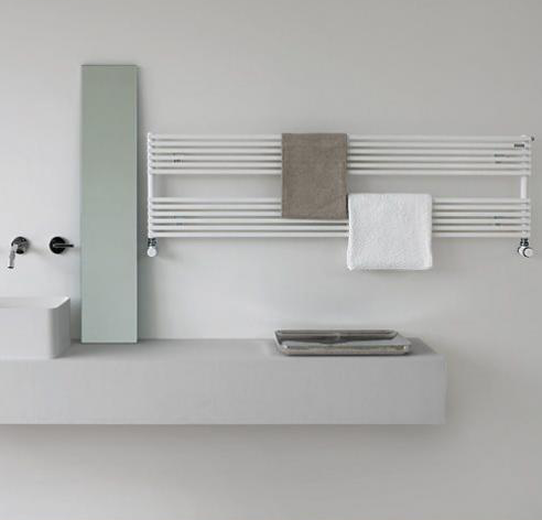 Sèche-serviettes horizontal blanc à tubes ronds, installé dans une salle de bains minimaliste avec plan vasque mural