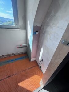 Salle de bains en rénovation avec réseaux électriques et plomberie pour le lave-mains et natte d’étanchéité posée au sol.
