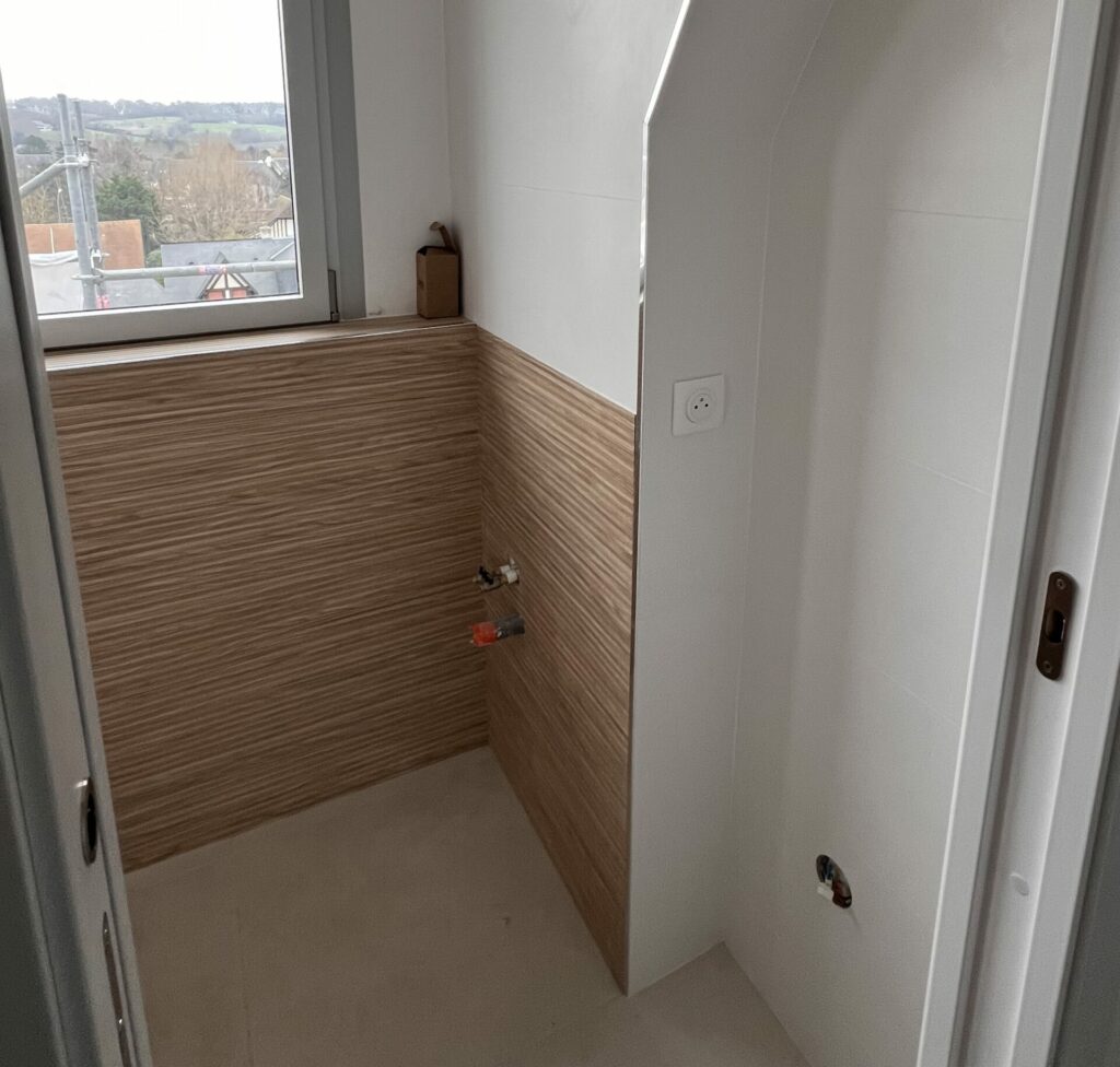 Salle de bains rénovée avec carrelage mural et joints terminés autour de la baignoire