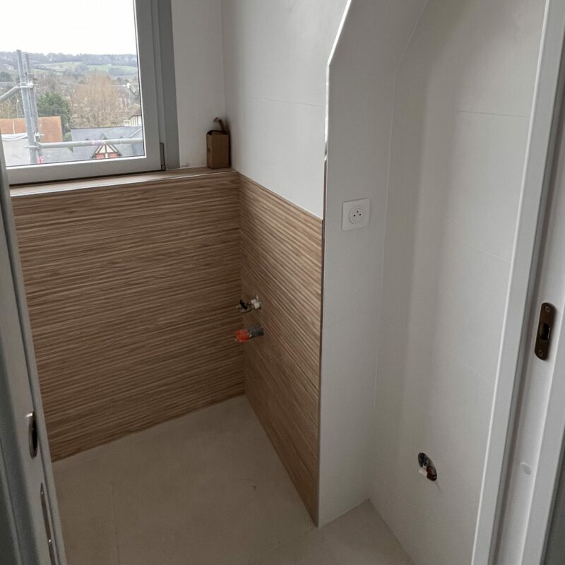 Salle de bains rénovée avec carrelage mural et joints terminés autour de la baignoire