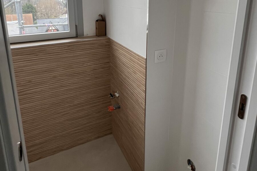 Salle de bains rénovée avec carrelage mural et joints terminés autour de la baignoire
