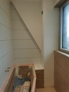 Salle de bains en rénovation, baignoire installée et murs en cours de carrelage.