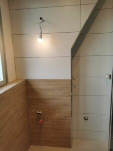 Travaux salle de bains en cours avec revêtements muraux posés et équipements prêts à être installés.