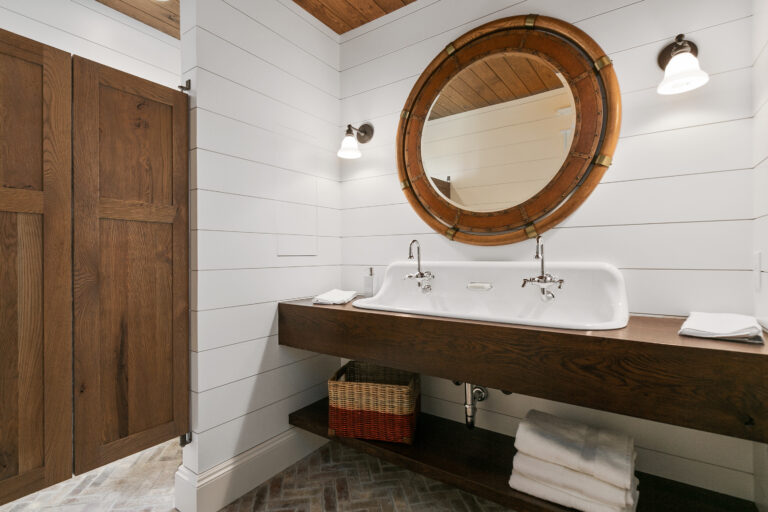 Salle de bains style campagne chic avec double vasque en céramique blanche, meuble suspendu en bois et miroir rond, ambiance naturelle et élégante.