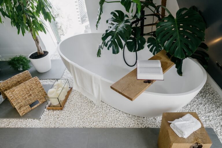 Salle de bains zen avec baignoire blanche, plantes vertes et matériaux naturels, créant une ambiance de détente et de bien-être